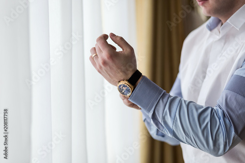 businessman checking time on his wrist watch, man putting clock on hand,groom getting ready in the morning before wedding ceremony