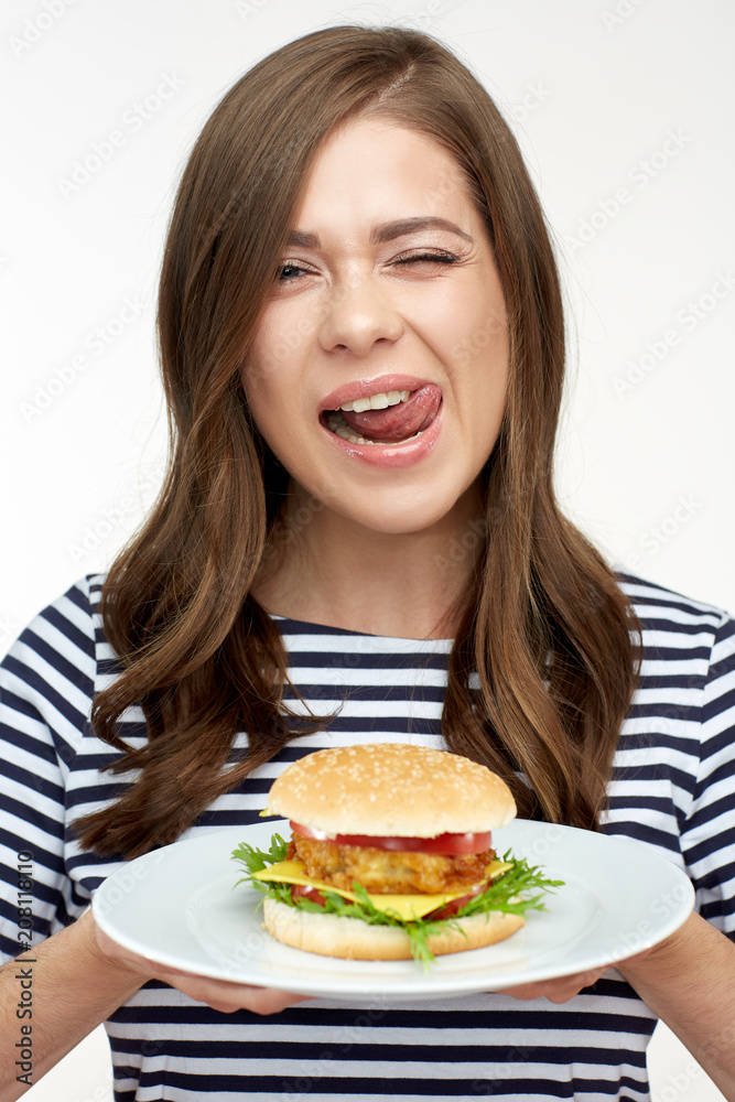 Happy woman licking lips holding burger on white plate