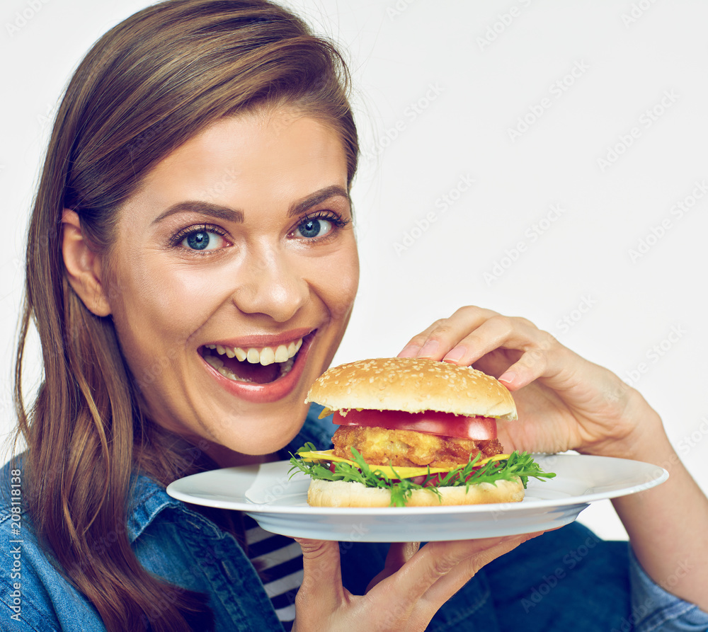 Smiling woman holding white plate with burger.