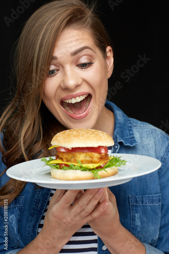 Happy woman holding burger on white plate.