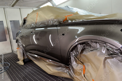 Painting the car in the workshop for body repair. Car covered with paper from hitting paint.