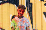 Teen smiling, is painted colorful with a graffiti