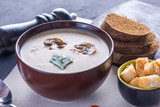 Mushroom cream soup in a brown plate on the table. Vegetarian traditional dish