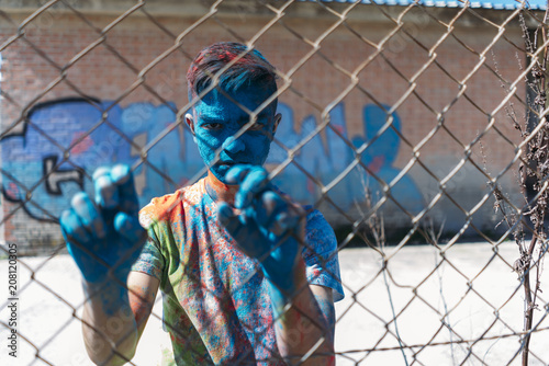 Teenager smiling behind the gate, is painted in colors