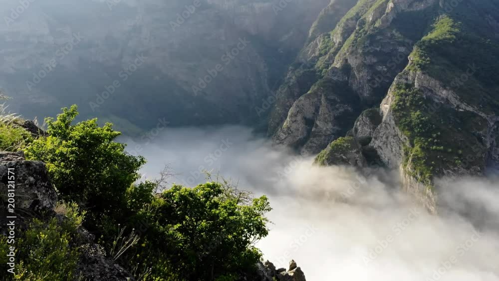 Flying over young man standing victoriously at the edge of the cliff at sunrise Flying over young man standing victoriously at the edge of the cliff at sunrise