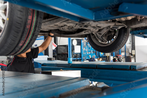 Auto mechanic checking car engine at the garage. Car service -  technician checking or fixing the engine of a car.