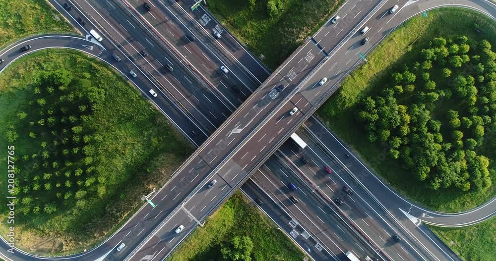 Cloverleaf interchange seen from above. Aerial view of highway road junction in the countryside with trees and cultivated fields. Bird's eye view.