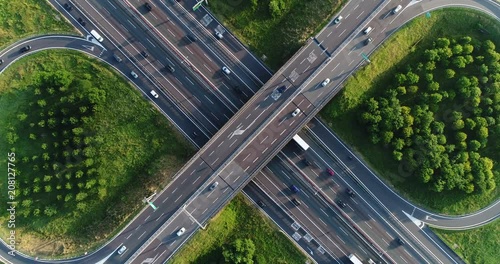 Cloverleaf interchange seen from above. Aerial view of highway road junction in the countryside with trees and cultivated fields. Bird's eye view.