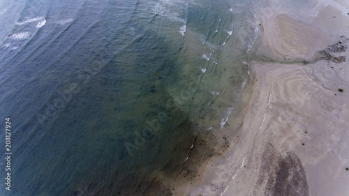 Small waves crashing on the sandy beach.