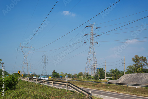 Power transmission pole parallel to the road with blue sky