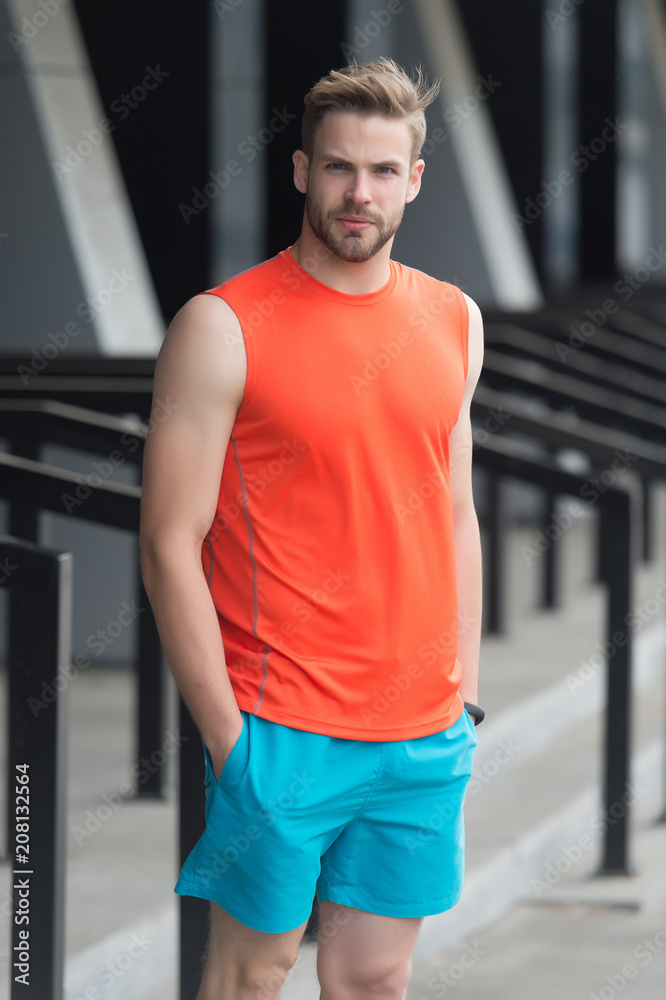 Man with bristle on serious face in sporty wear, urban background. Sport  fashion concept. Guy bearded and attractive cares about appearance. Man  with beard or unshaven guy in stylish sport clothes Stock