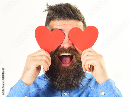 Blinded by love concept. Man with beard holds red hearts