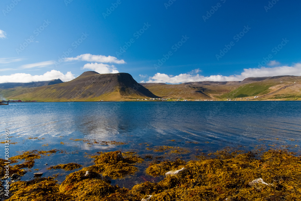 Mountain landscape seen from sea in isafjordur, iceland. Hilly coastline on sunny blue sky. Summer vacation on scandinavian island. Discover wild nature. Wanderlust and travelling concept
