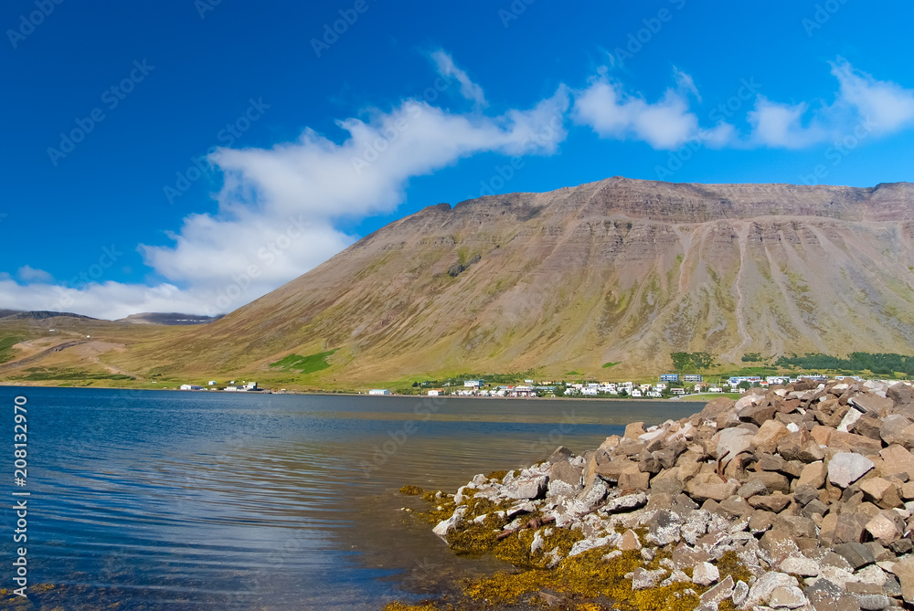 Hilly coastline on sunny blue sky in isafjordur, iceland. Mountain landscape seen from sea. Summer vacation on scandinavian island. Discover wild nature. Wanderlust and travelling concept