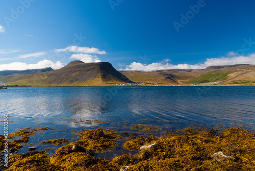 Mountain landscape seen from sea in isafjordur, iceland. Hilly coastline on sunny blue sky. Summer vacation on scandinavian island. Discover wild nature. Wanderlust and travelling concept