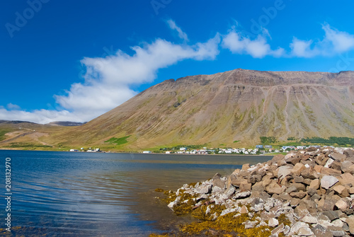 Hilly coastline on sunny blue sky in isafjordur  iceland. Mountain landscape seen from sea. Summer vacation on scandinavian island. Discover wild nature. Wanderlust and travelling concept