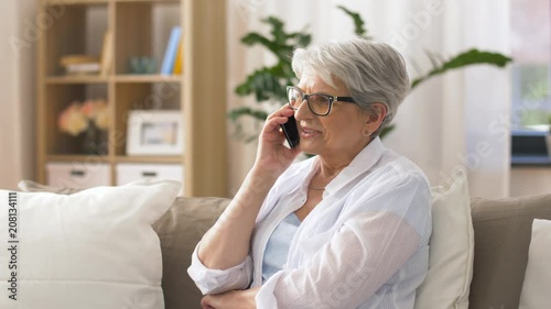 technology, communication and people concept - happy senior woman calling on smartphone at home