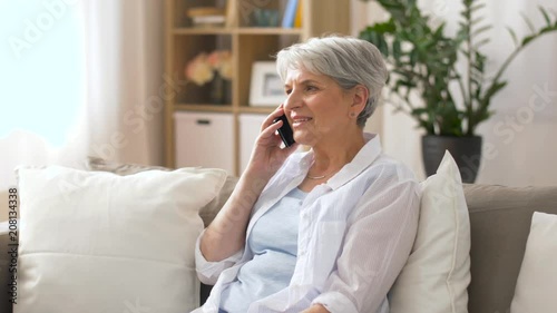 technology, communication and people concept - happy senior woman calling on smartphone at home