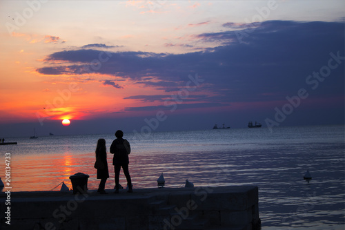 Картината върху платно Loving couple is standing at the pier during the sunset
