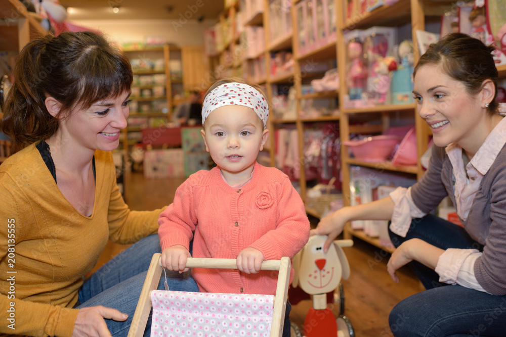 mother and daughter with attractive vendor in toy store