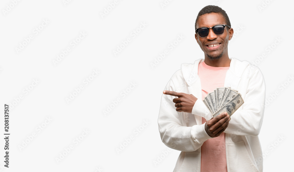 African man holding dollar bank notes pointing away side with finger African man holding dollar bank notes pointing away side with finger
