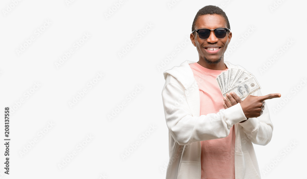 African man holding dollar bank notes pointing away side with finger African man holding dollar bank notes pointing away side with finger