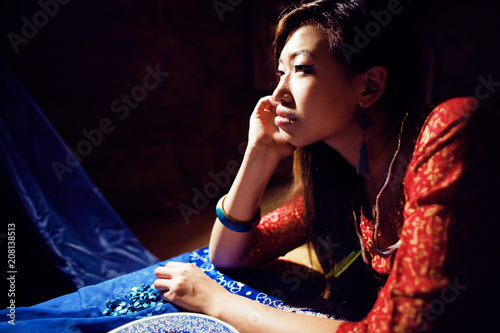 young pretty asian girl in bright colored interior on carpet. li