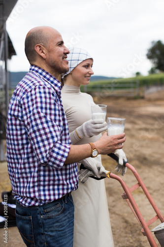 rural country couple of farmers posing with glass of milk at cowfarm photo