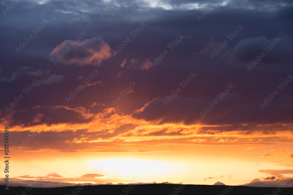 intensive clouds and golden sun beam at sunset horizon