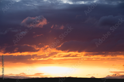 intensive clouds and golden sun beam at sunset horizon