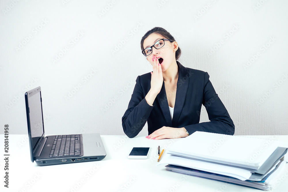 attractive displeased unhappy brunette businesswoman in a stylish business suit working in the office with a laptop and bored wants to sleep. concept of lack of sleep and deadline attractive displeased unhappy brunette businesswoman in a stylish business suit working in the office with a laptop and bored wants to sleep. concept of lack of sleep and deadline