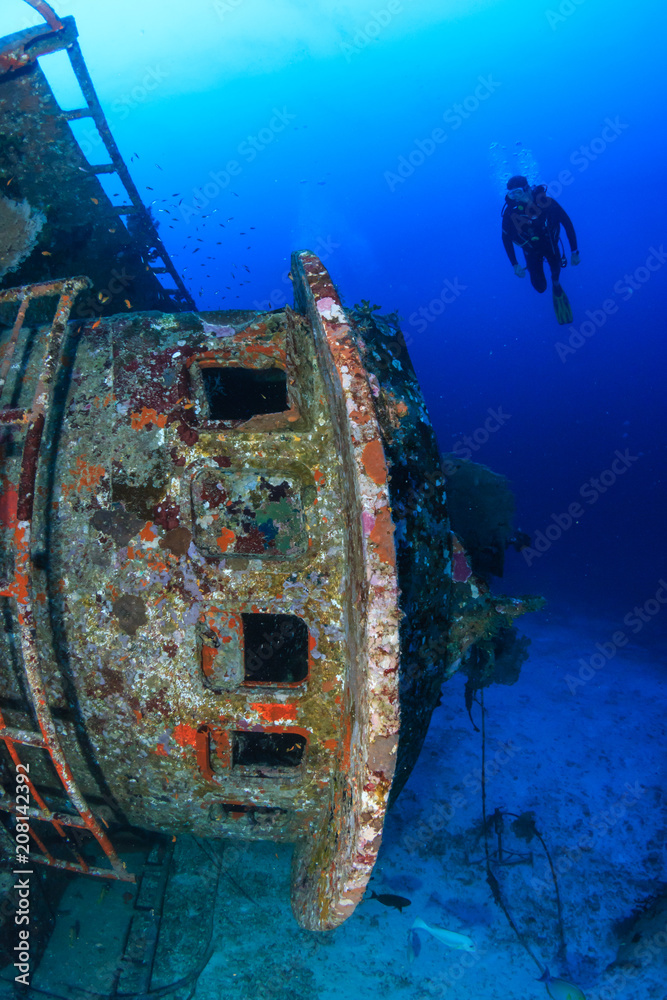 SCUBA diver next to a large underwater shipwreck in a tropical ocean