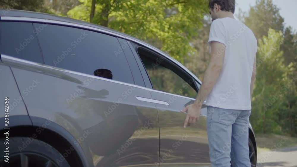 Young man can't open a door of modern car Young man can't open a door of modern car