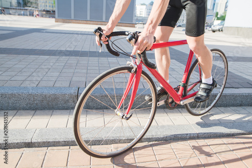 Man comes down from the curtain on a city red road bike. A cyclist cycling around the city. Traveling around the city on a bicycle.