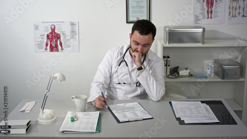Thinking out loud. Thoughtful young bearded doctor in medical cabinet.