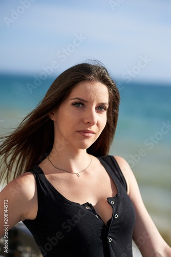 Young sexy brunette in a black dress near the sea