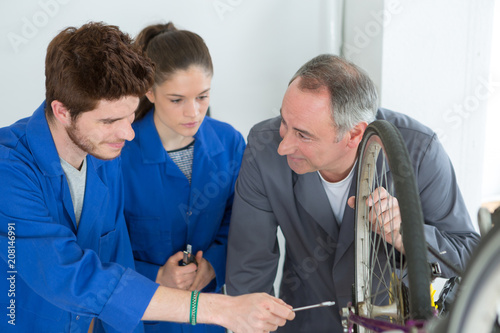 bicycle mechanic and apprentices repairing a bike in workshop