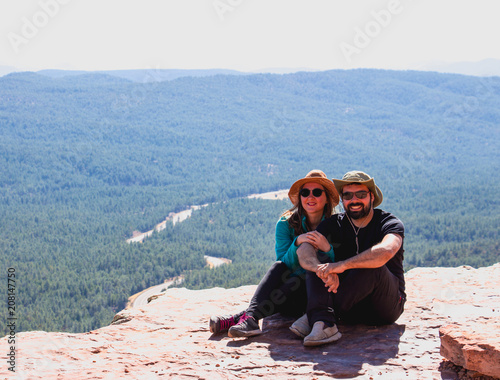 smiling young couple sitting on the edge and relaxing in the forest