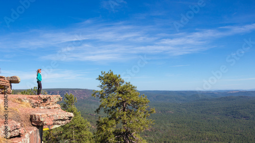 young woman standing at the edge and wathching forest landscape
