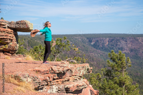 happy young woman open her arms, standing against to wind at the edge