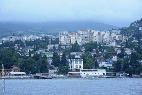 View of the town Gurzuf: sea front, beach, buildings and mountains in the fog. June 10, 2017. Gursuf, Crimea photo