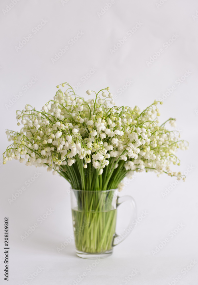bouquet lily-of-the-valley stands on isolated background in mug with water - obrazy, fototapety, plakaty 