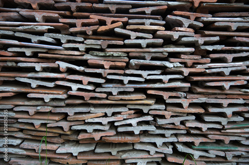 Bales ceramic shingles for roofing. Stack of old ceramic roof tiles, textured background.