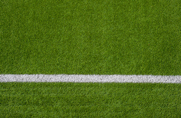 Photo of a green synthetic grass sports field with white line shot from above.