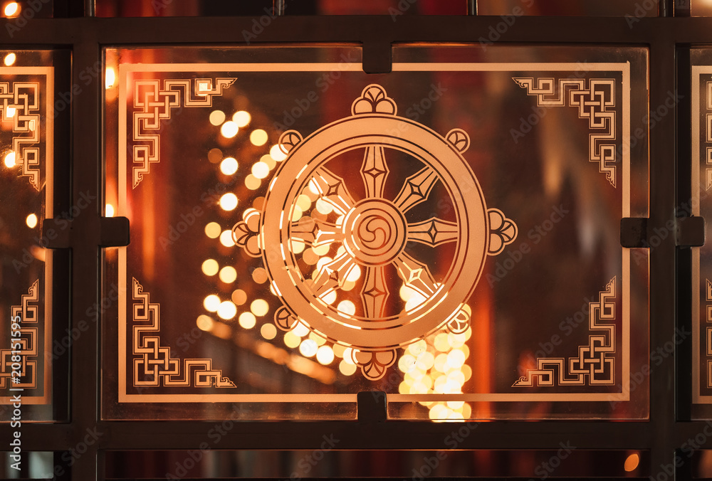 Φωτογραφία One of 8 Buddhist good symbols - a wheel of the teaching Dharmachakra against the background of fires of ritual candles