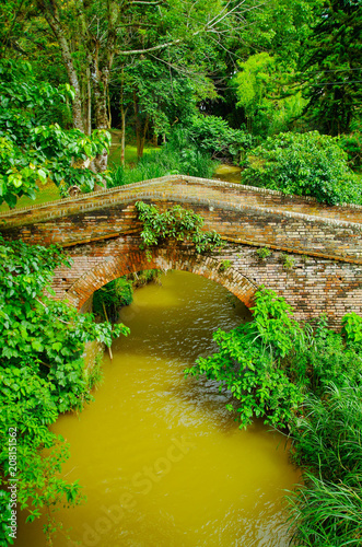 Outdoor view of brick bridge crossing over a smalll river located inside the forest in colonial city Popayan photo
