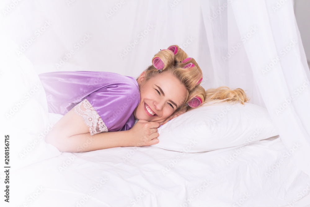 Happy girl enjoying nap time smiling wide. Young lady with hair curled lying on white pillow giggling in her bedroom. Happy girl enjoying nap time smiling wide. Young lady with hair curled lying on white pillow giggling in her bedroom.
