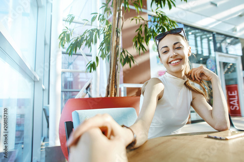 First person view of man holding hand of his smiling woman. Focus on the woman photo