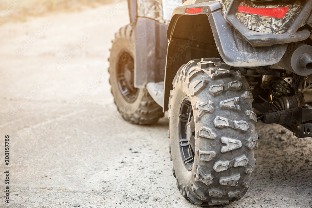 Obraz premium Close-up tail view of ATV quad bike. Dirty whell of AWD all-terrain vehicle. Travel and adventure concept.Copyspace.Toned
