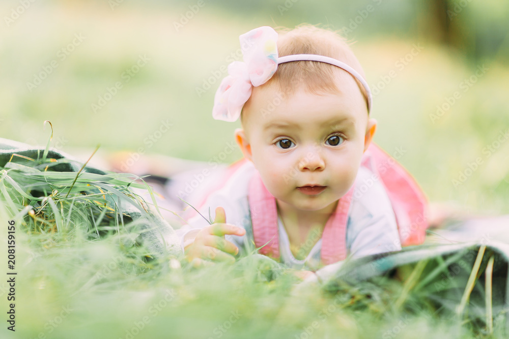 Portrait of happy joyful child in pink dress over green grass background. Happy little baby girl in the park. Family concept Portrait of happy joyful child in pink dress over green grass background. Happy little baby girl in the park. Family concept